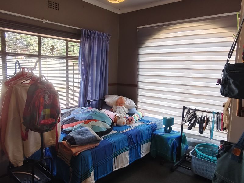 A bedroom featuring dual window treatments with horizontal blinds and curtain rails, providing natural light and privacy.