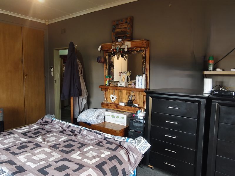 A bedroom featuring built-in wooden cupboards and dark wall finishes, requiring cosmetic updates to improve the overall aesthetic and condition.