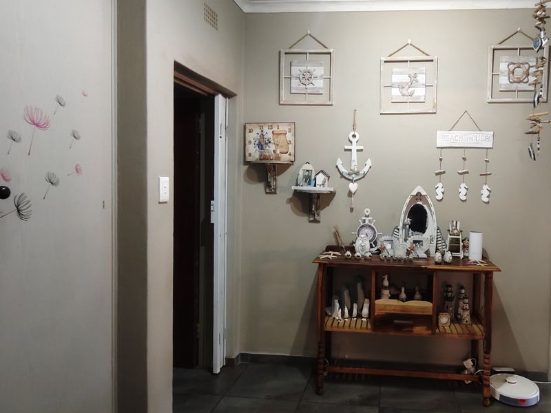 A functional hallway area featuring tiled flooring and a built-in cupboard, providing access to adjacent rooms within the home.