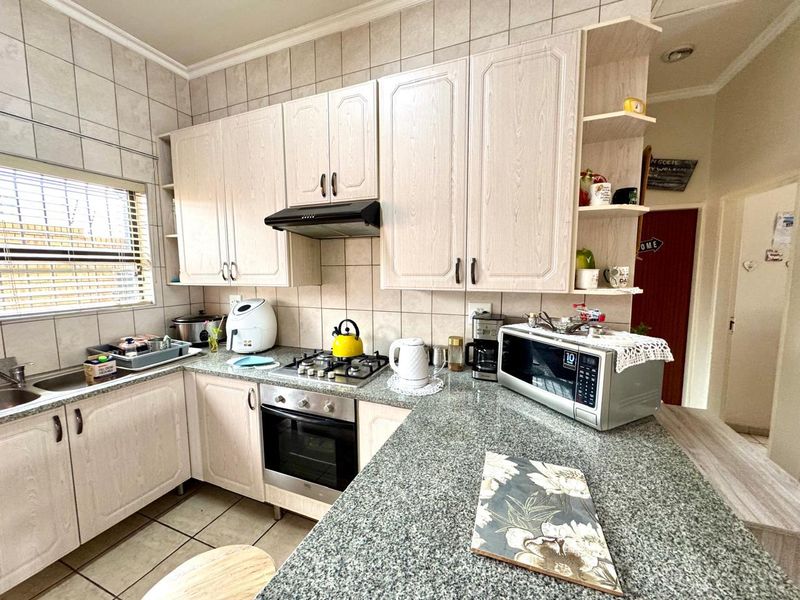 Functional kitchen featuring granite countertops, built-in oven, gas hob, extractor fan, and ample cabinetry with a tiled backsplash and flooring.