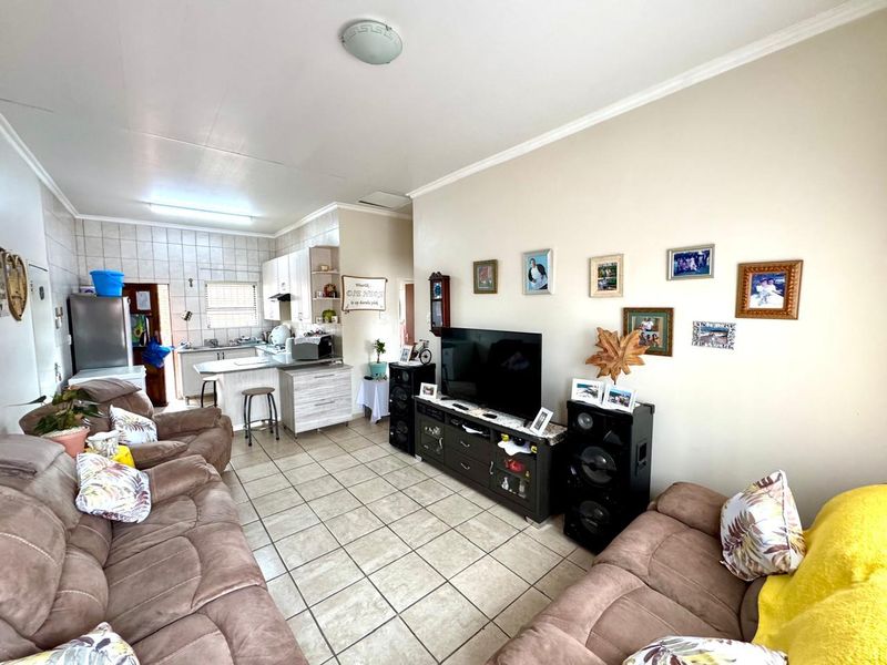 Open-plan living area featuring tiled flooring and a functional kitchen with breakfast bar, providing a combined space for cooking and relaxation.