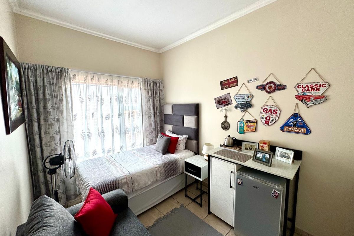 A compact bedroom featuring tiled flooring and coved ceilings, currently furnished as a studio-style living space.
