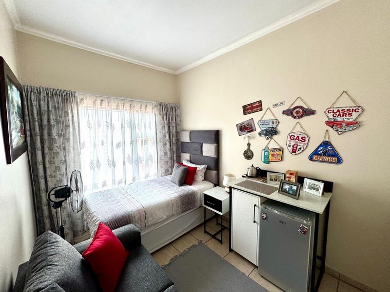 A compact bedroom featuring tiled flooring and coved ceilings, currently furnished as a studio-style living space.