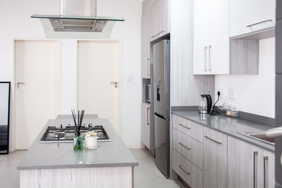 Modern kitchen featuring a central island with a gas hob, sleek cabinetry, stone countertops, and integrated appliances in a bright, contemporary space.