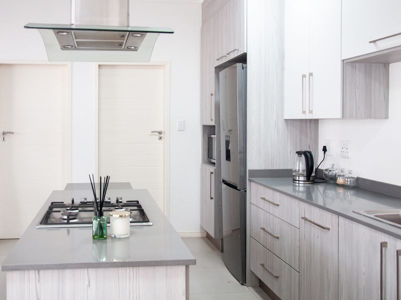 Modern kitchen featuring a central island with a gas hob, sleek cabinetry, stone countertops, and integrated appliances in a bright, contemporary space.