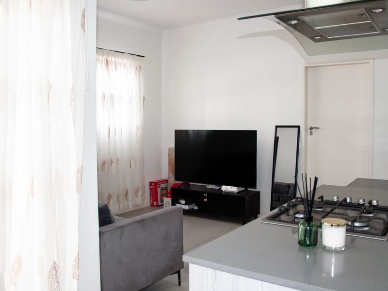 Open plan living area featuring a modern kitchen island with a gas hob and extractor fan, seamlessly flowing into the lounge space.