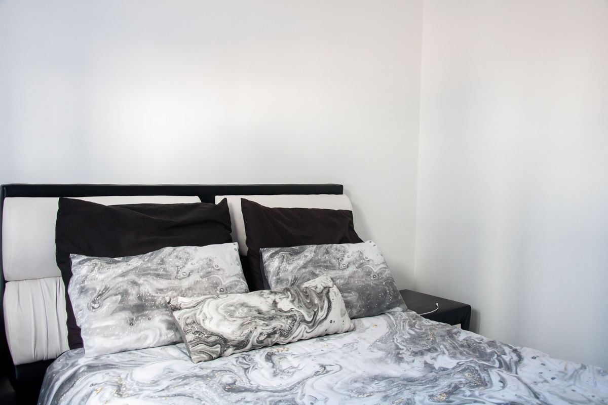 A bedroom interior featuring a bed with a headboard against a plain white wall.