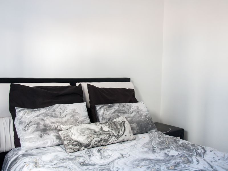 A bedroom interior featuring a bed with a headboard against a plain white wall.