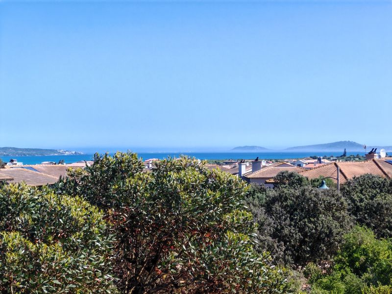 A scenic elevated view overlooking the surrounding neighborhood rooftops with a clear blue ocean and distant coastline in the background.