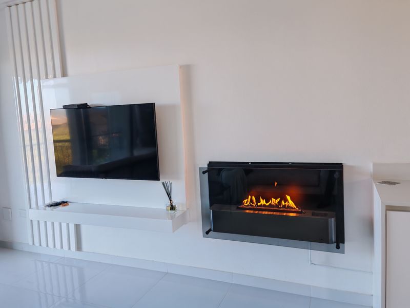 Modern living room featuring a sleek wall-mounted fireplace and a minimalist built-in media console with glossy white finishes.