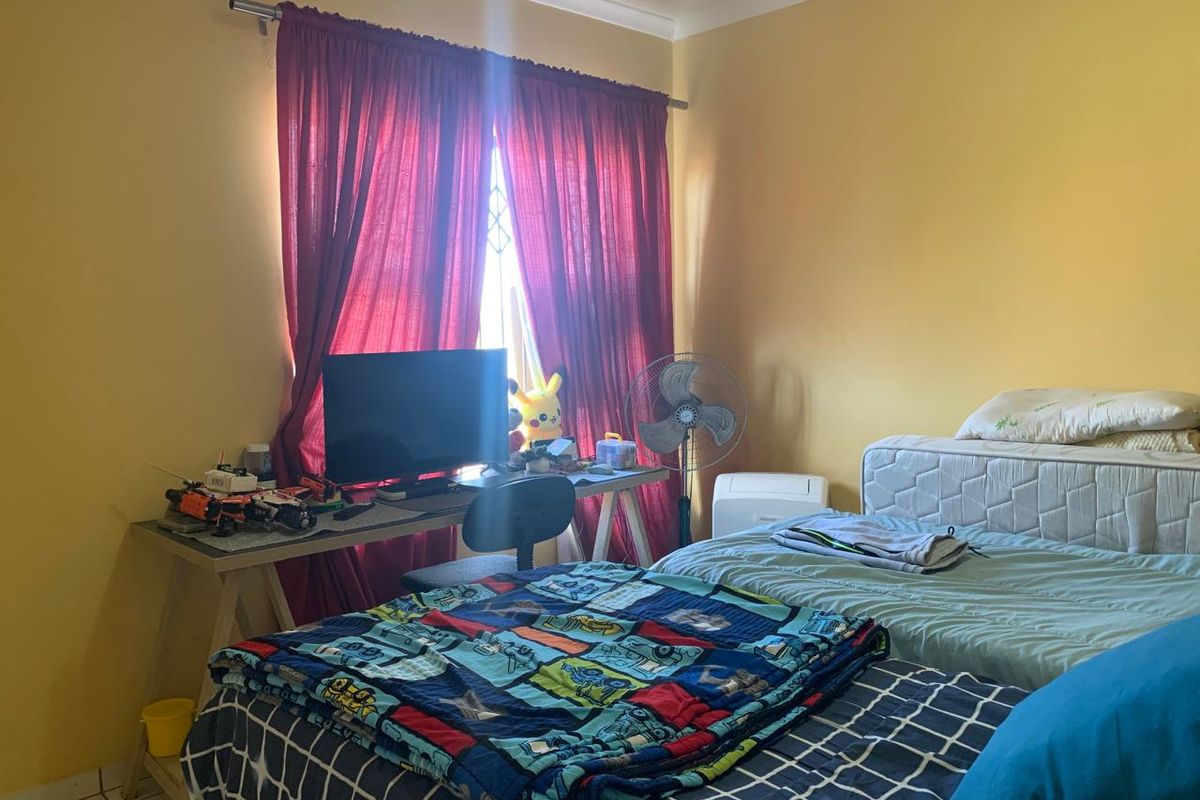 A bedroom featuring yellow walls, a window with a security gate, and cove cornicing.