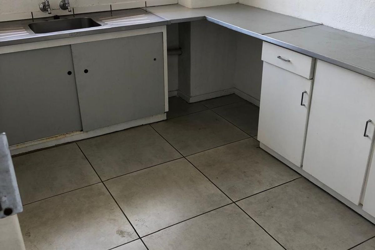 A functional kitchen space featuring built-in cabinetry, a stainless steel sink, and tiled flooring, ready for renovation or modernization.
