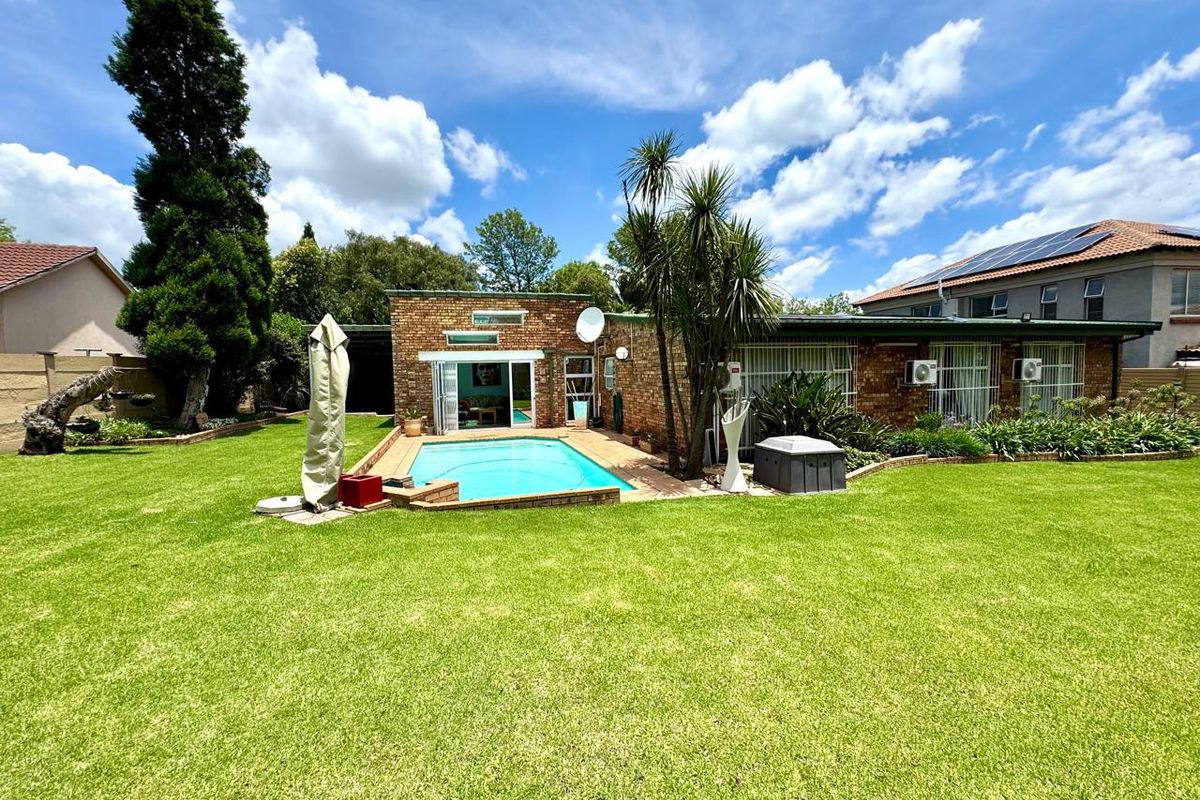 Rear view of the property featuring a well-maintained lawn, a swimming pool with paved surround, and brick exterior walls with sliding door access.