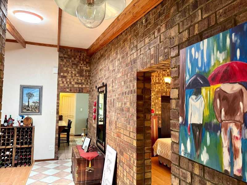 A characterful hallway featuring exposed brick walls, timber ceiling beams, and an arched transition leading into adjacent living spaces.