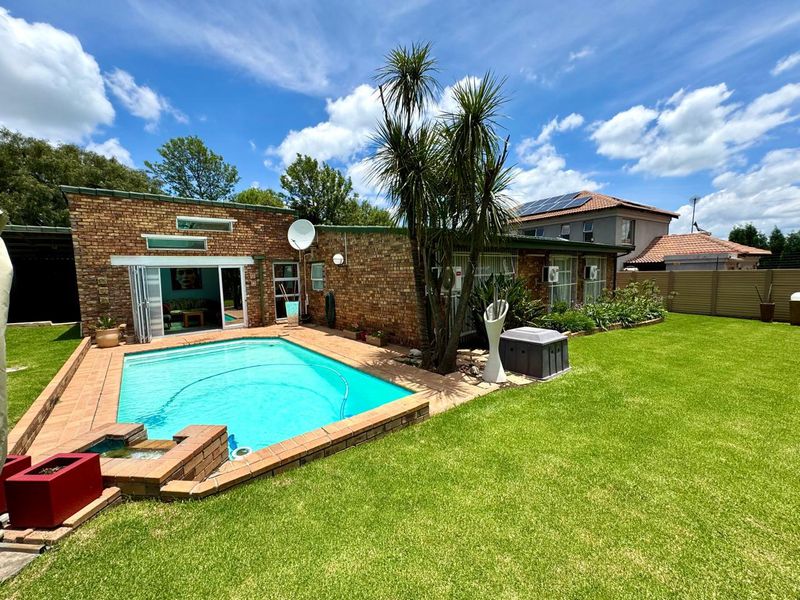 A well-maintained rear garden featuring a swimming pool, brick exterior facade, and bi-fold doors leading into the home.