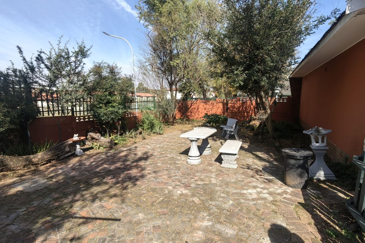 A rear garden area featuring a brick-paved patio space enclosed by a perimeter wall and fencing, offering potential for outdoor landscaping and entertainment.