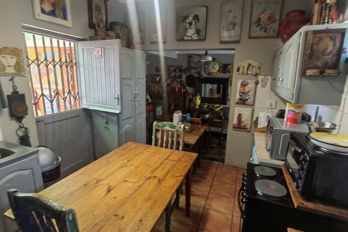 A functional kitchen area featuring tiled flooring, built-in cabinetry, and a security gate, providing a practical space for cooking and dining.