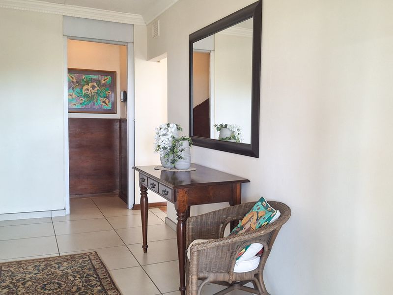 A bright hallway featuring neutral walls, tiled flooring, and decorative crown molding, providing a clean transition between living spaces.