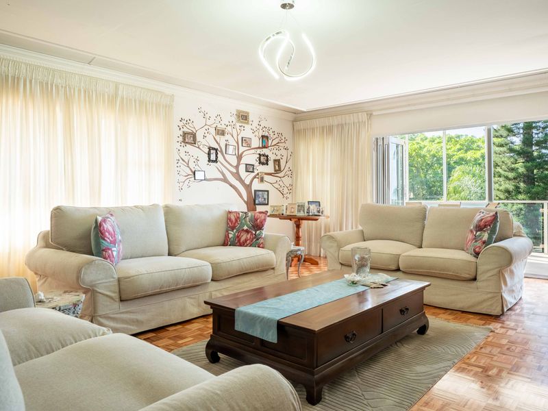 Spacious living room featuring classic parquet flooring, elegant ceiling cornicing, and bi-fold doors that open to an outdoor balcony area.