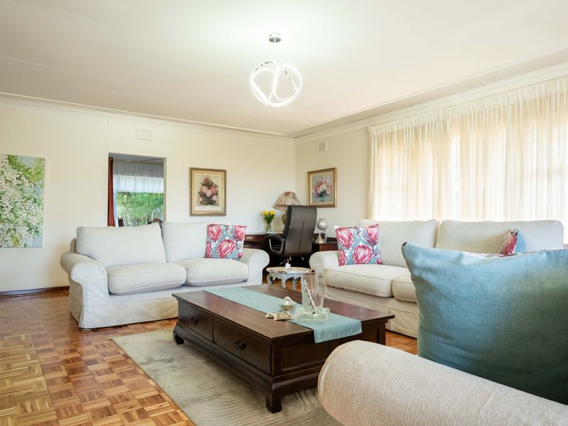 A well-maintained living room featuring classic parquet flooring, coved cornicing, and a contemporary pendant light fixture, creating a warm and inviting atmosphere.