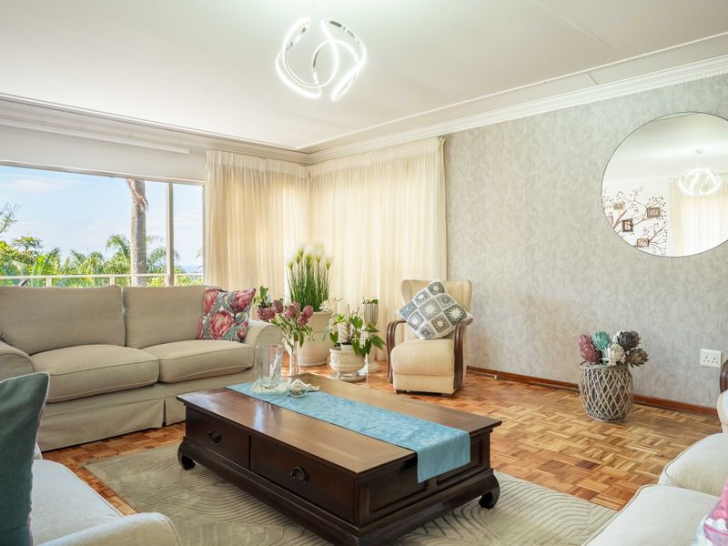 A bright and inviting living room featuring classic parquet flooring, crown molding, and a large sliding glass door that provides ample natural light.
