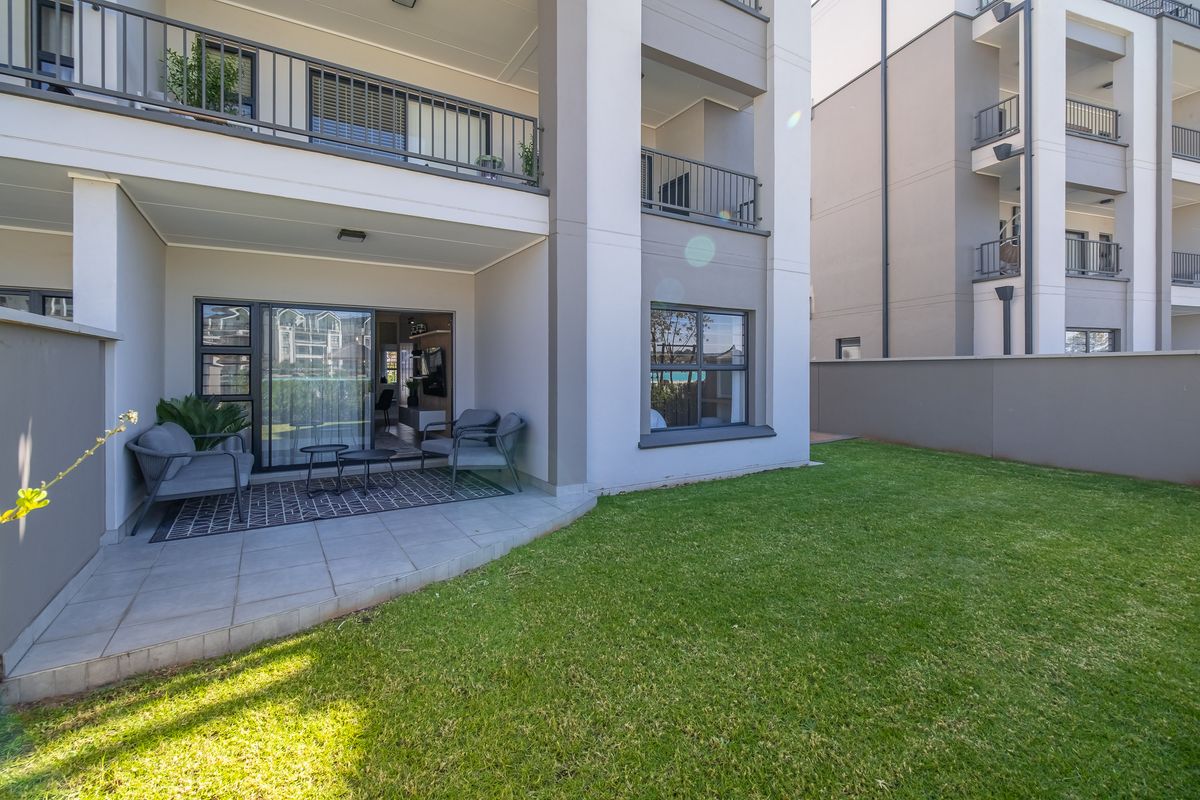 A ground floor townhouse unit featuring a paved patio area and a private garden, with access to the living space via sliding glass doors.