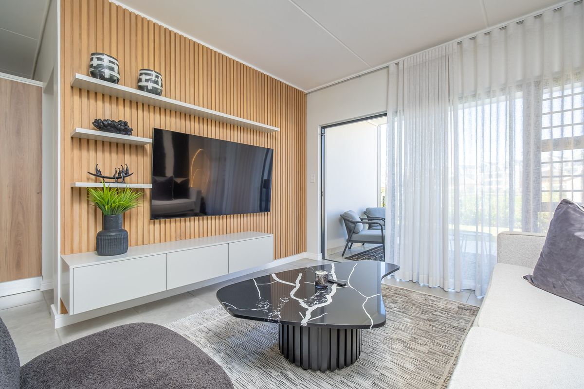 Modern living room featuring a decorative timber slat feature wall, built-in media cabinetry, and large sliding glass doors leading to a private patio.