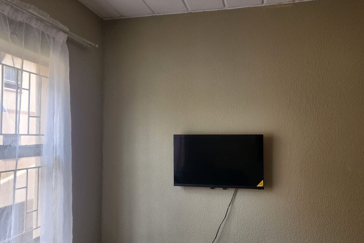 A living room area featuring a textured ceiling and a window fitted with security bars.