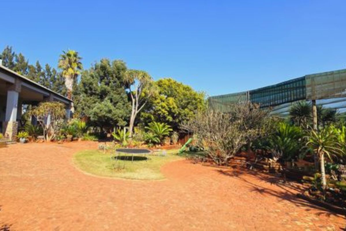 Spacious rear garden area featuring a paved patio, established landscaping, and a large covered outdoor structure.