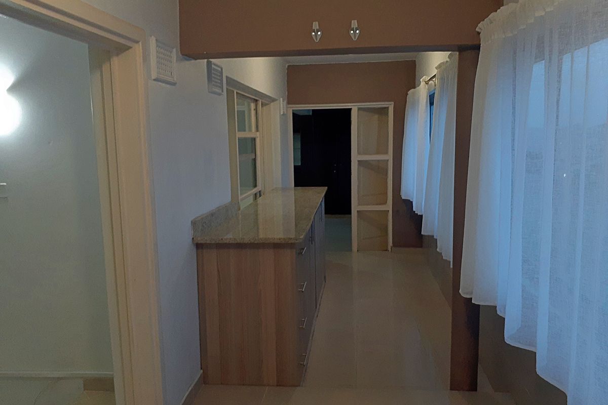 A functional kitchen area featuring granite countertops, built-in cabinetry, and tiled flooring, offering a clean and practical layout for culinary activities.