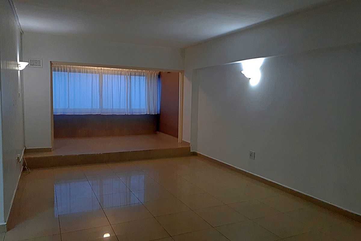 An empty, open-plan living area featuring tiled flooring and a raised platform section, providing a versatile space for interior design.