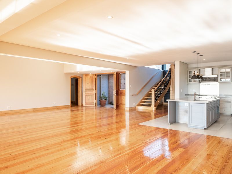 Spacious open-plan living area featuring polished hardwood floors, a modern kitchen island with cabinetry, and a feature staircase.