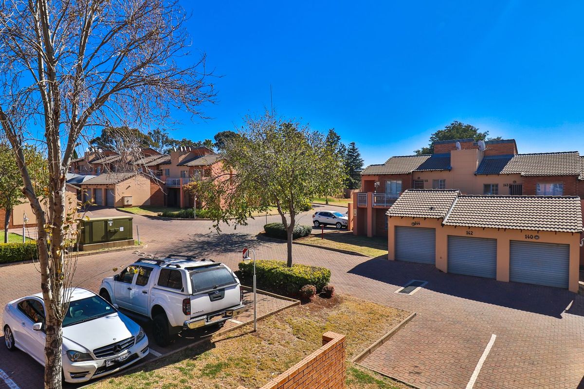 Elevated view of a residential apartment complex featuring brick-paved driveways, multiple garage units, and well-maintained communal outdoor spaces.