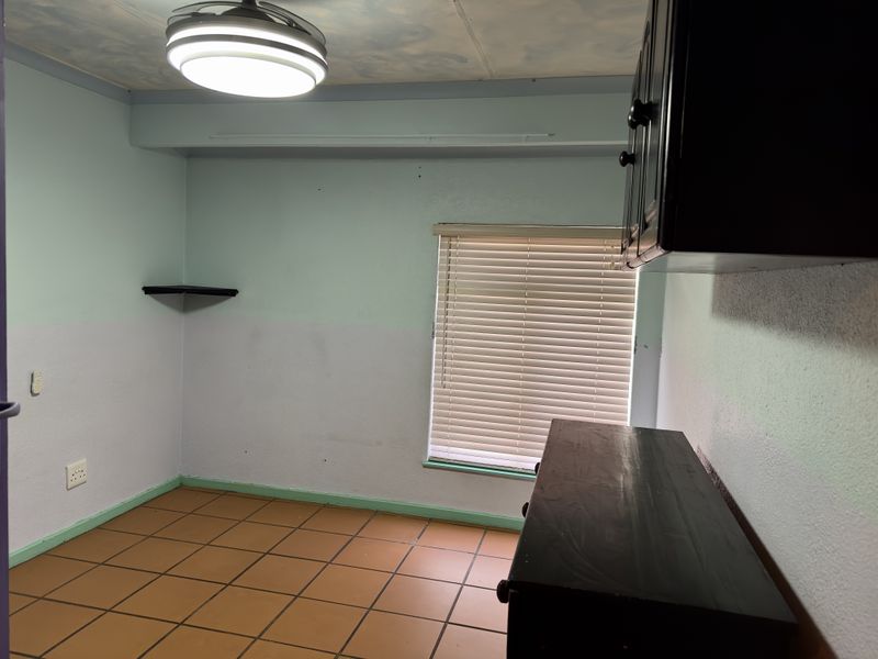 An empty bedroom featuring tiled flooring, a ceiling fan, and built-in cabinetry, offering a blank canvas for potential renovation and interior design updates.