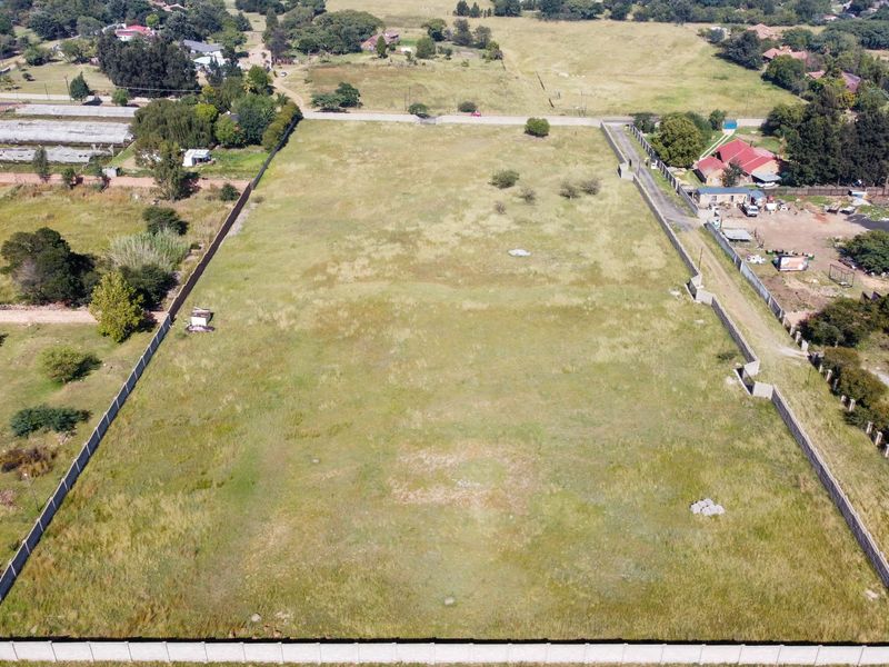 An aerial view of a large, vacant residential plot enclosed by perimeter walls, offering a clear perspective of the land and surrounding neighborhood.