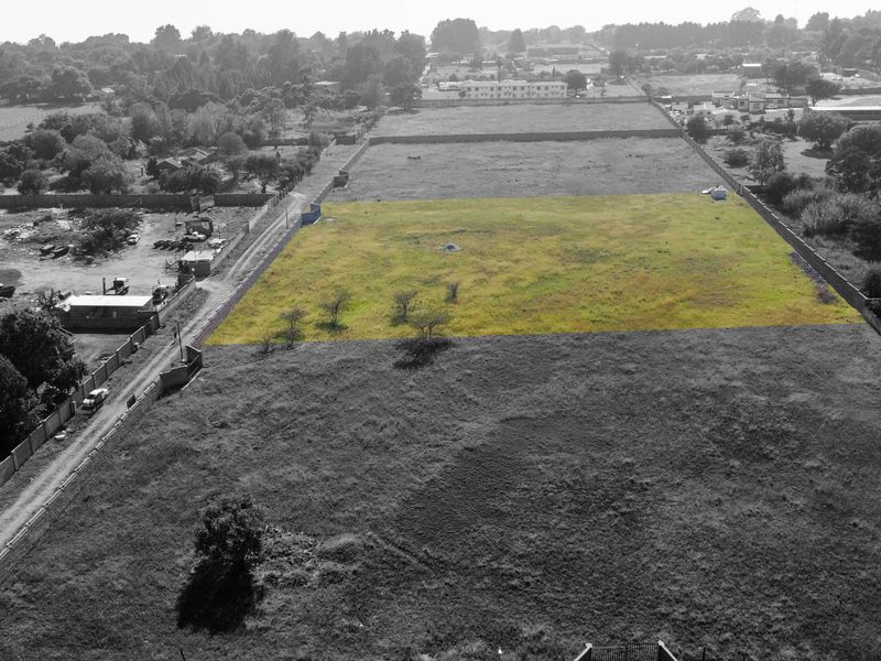 Aerial view of a vacant residential plot with perimeter boundary walls, highlighting the land parcel in a suburban setting.