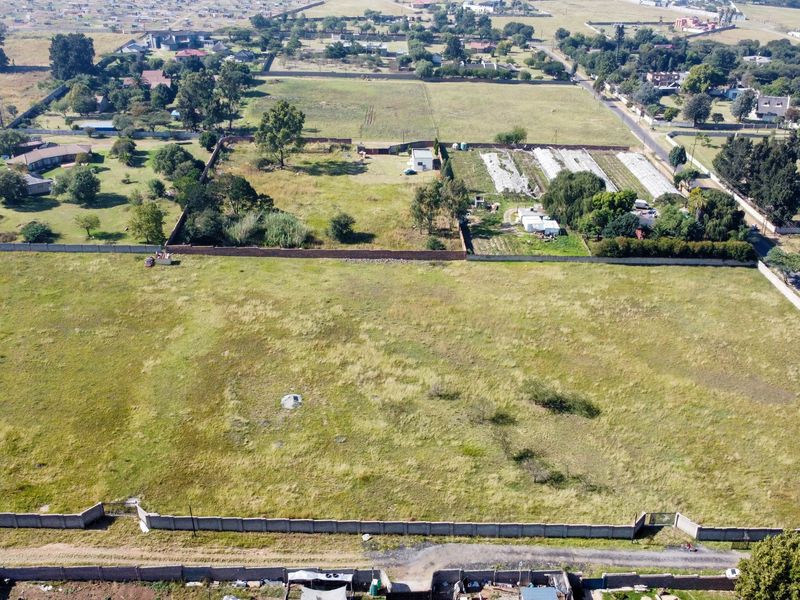 An aerial view of a large, vacant residential plot featuring perimeter walling and surrounding neighborhood infrastructure.