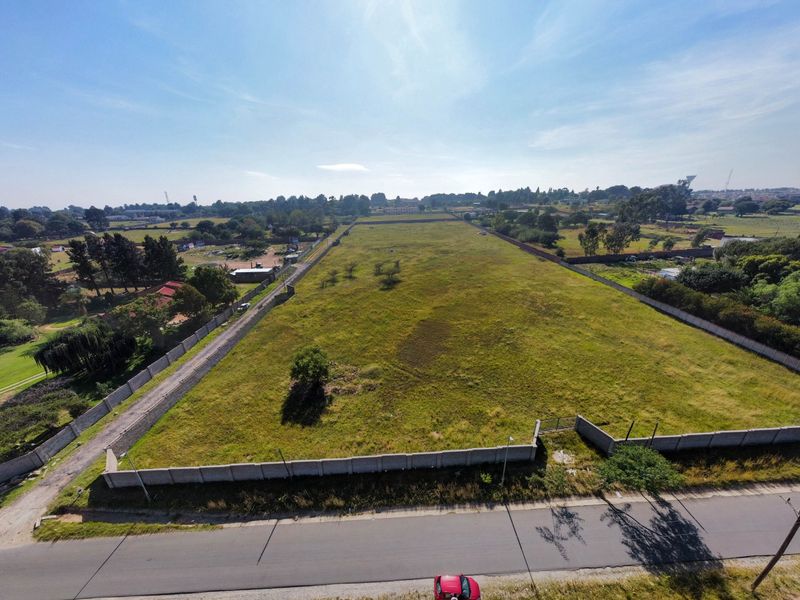 An aerial view of a large, vacant residential plot enclosed by perimeter walls, offering significant development potential in a well-established neighborhood.