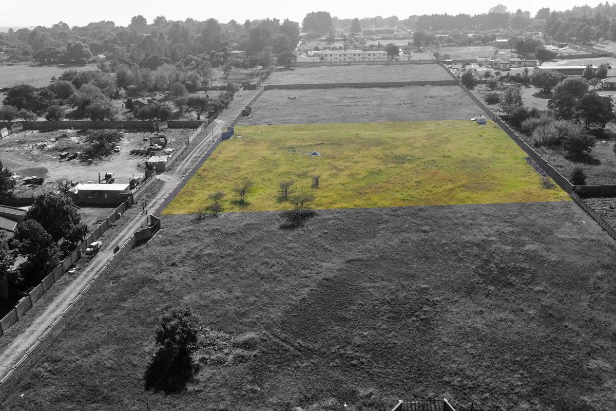 Aerial view of a vacant residential plot with perimeter boundary walls, highlighting the land parcel in a suburban setting.