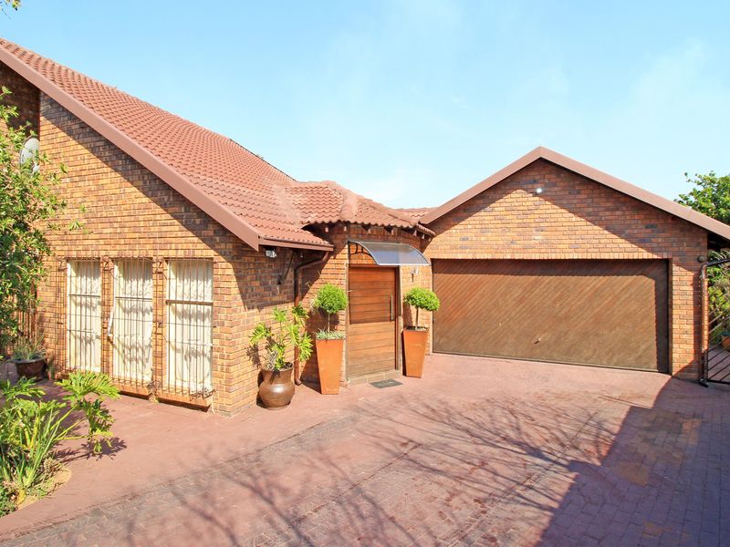 Front elevation of a face brick house featuring a paved driveway, double garage, and a covered entrance with a wooden door.