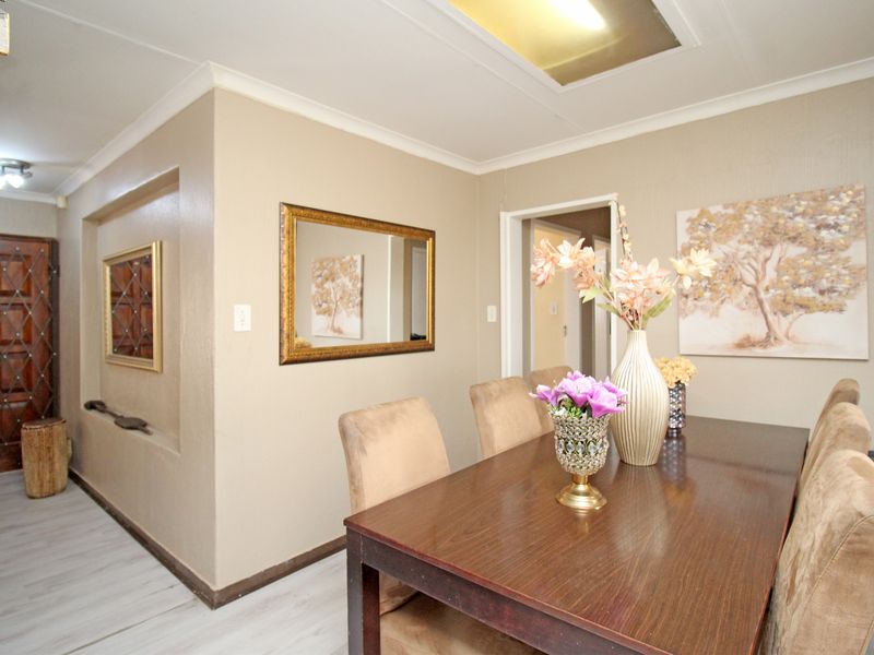 Dining area featuring laminate flooring, a recessed wall niche, and neutral wall tones, providing a functional space for family meals.
