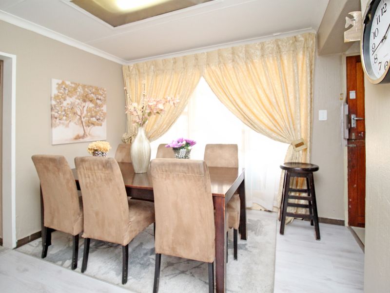 A dining room featuring laminate flooring, recessed ceiling lighting, and coving, providing a functional space for family meals.