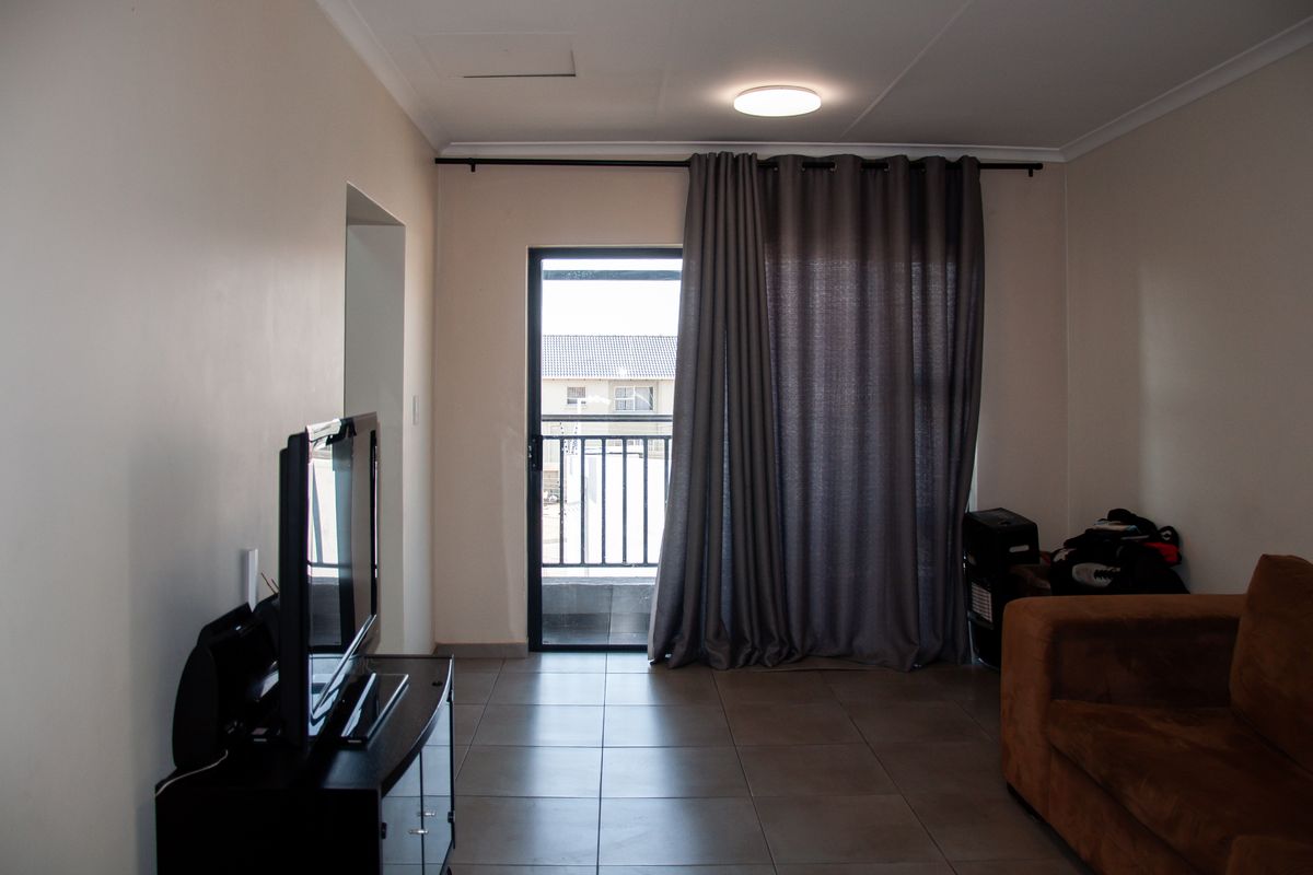 A living room featuring tiled flooring and a sliding glass door providing access to a balcony.