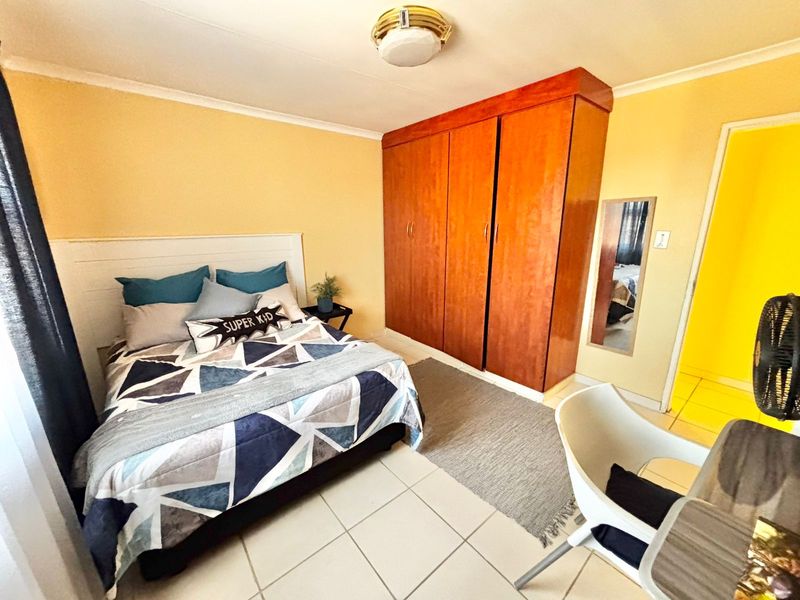 A bedroom featuring tiled flooring, a built-in wooden wardrobe, and a ceiling light fixture.