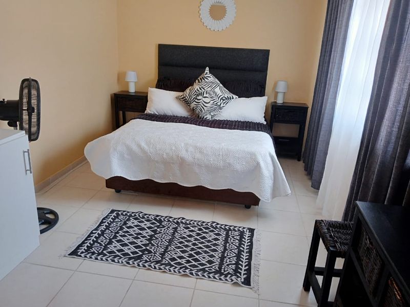 A well-lit bedroom featuring neutral wall tones and tiled flooring, providing a comfortable and functional sleeping space.