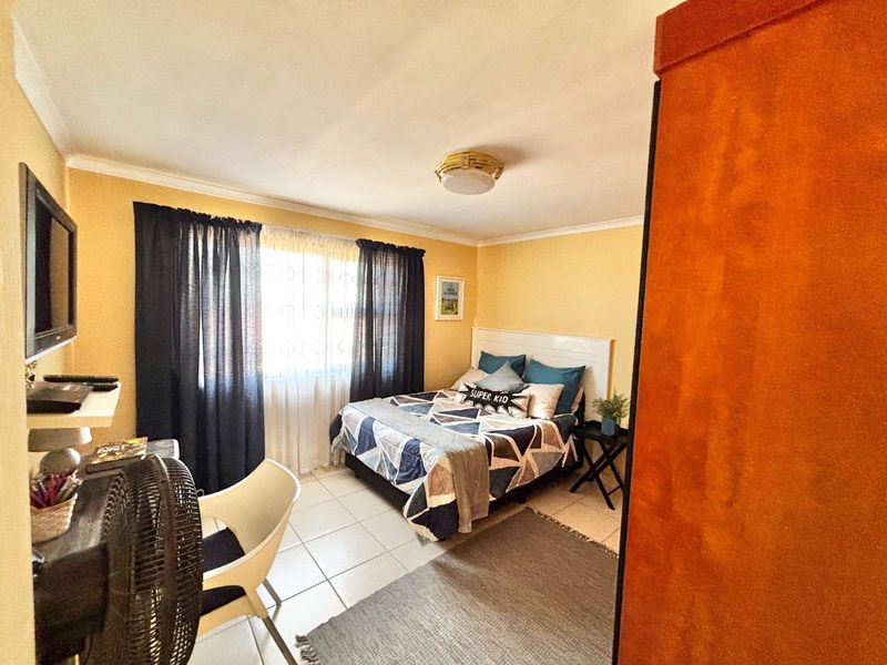 A functional bedroom featuring tiled flooring, neutral wall finishes, and a central ceiling light fixture, providing a comfortable and practical living space.