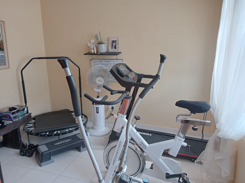 A dedicated home gym space featuring tiled flooring and neutral wall finishes, currently utilized for fitness equipment.