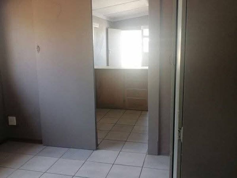 An empty bedroom featuring tiled flooring and a sliding door leading to an adjacent space with built-in cabinetry.