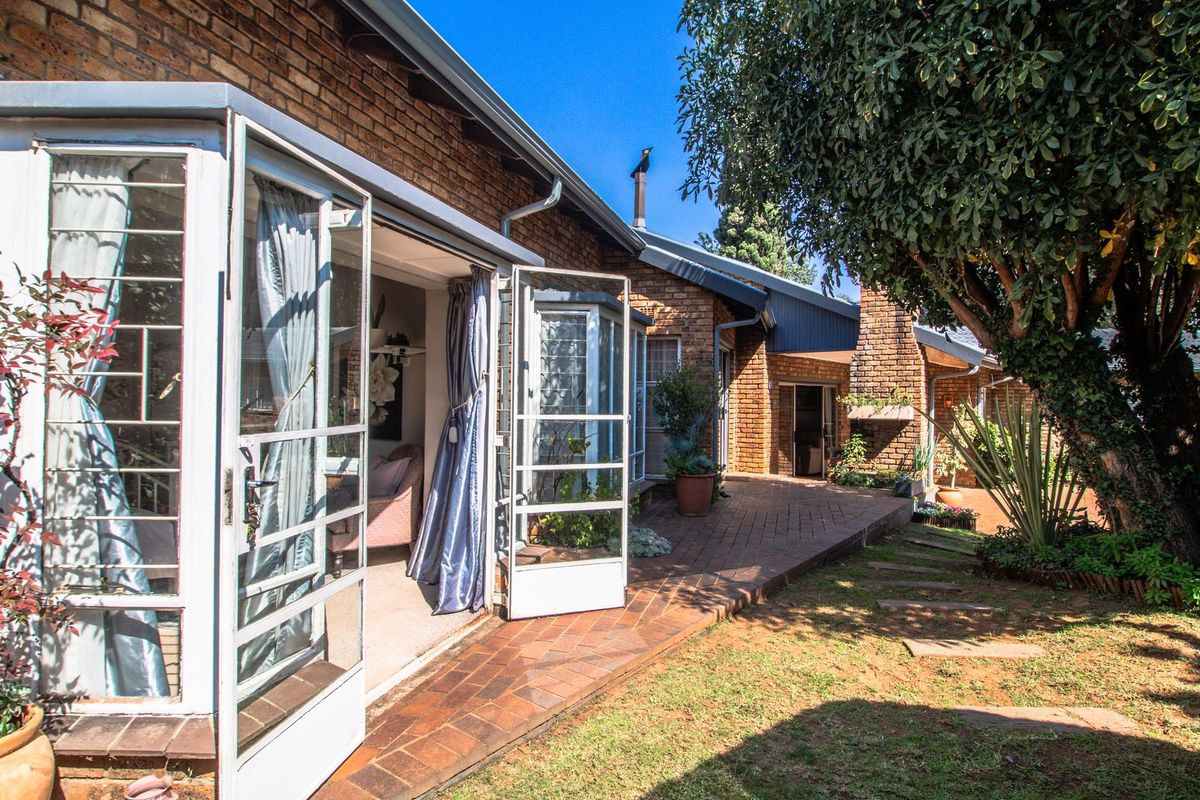 Rear view of the property featuring a brick facade, paved patio area, and access to the interior through multiple sets of french doors.