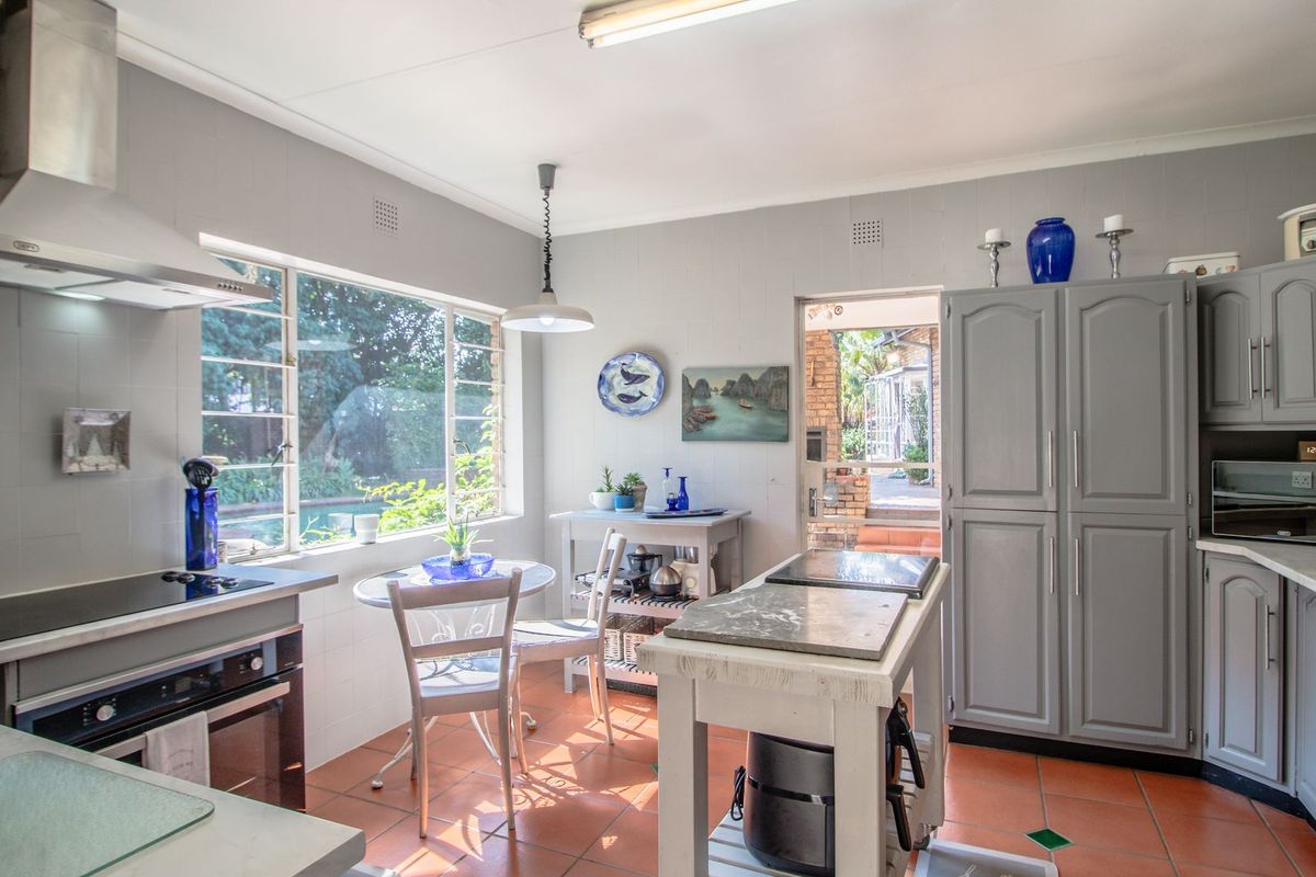A functional kitchen featuring grey cabinetry, tiled flooring, built-in oven and hob, and direct access to the outdoor patio area.